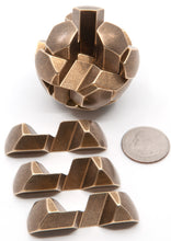 Load image into Gallery viewer, Metal Gumball spherical puzzle with three brass pieces removed and laid out beside the puzzle.