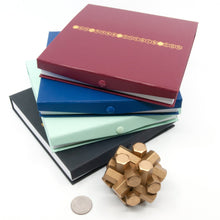 Load image into Gallery viewer, Assembled puzzle in front of the four boxes that come with each set. Three full puzzles + bonus pieces and book to make many more