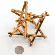 Load image into Gallery viewer, Assembled brass Nova Plexus interlocking puzzle sculpture with US quarter for size.  

