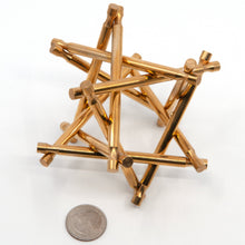 Load image into Gallery viewer, Assembled brass Nova Plexus interlocking puzzle sculpture with US quarter for size.