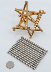 Assembled Brass Nova Plexus Puzzle with a disassembled, but very neatly arranged, stainless steel version and a US quarter in the foreground.